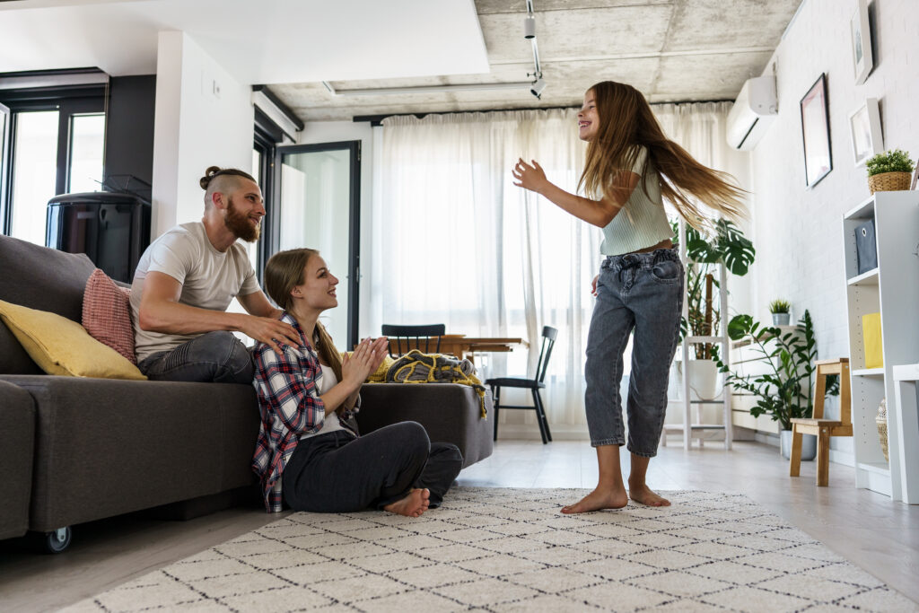 Daughter was dancing and entertaining in front of her parents in the living room.